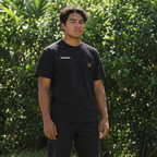 Black tee model in a leafy Hawaiian setting